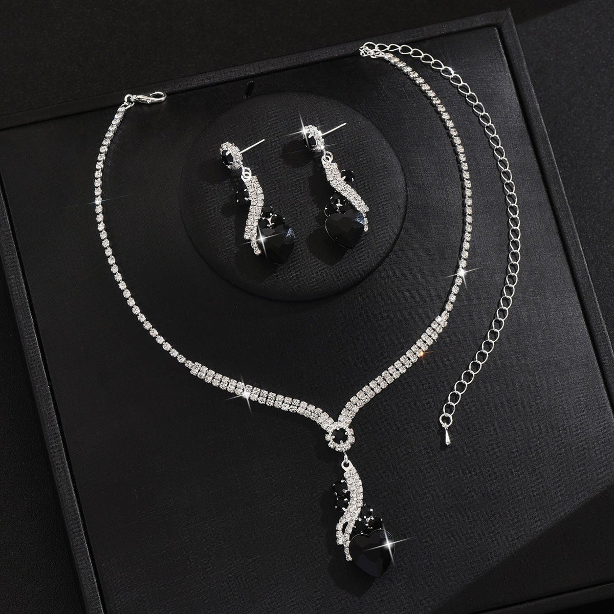 Black-detail necklace and earrings on a black display