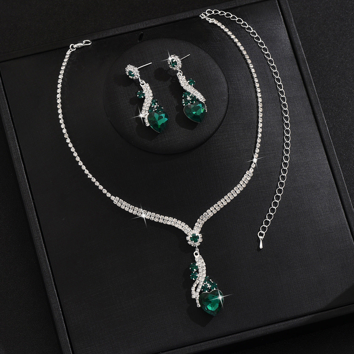 Green-detail necklace and earrings on a black display